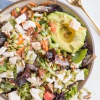 Amazing Filling Salad Recipe with chicken, avocado, spring greens, carrot, pumpkin seeds, pecans, green onion, and tomato