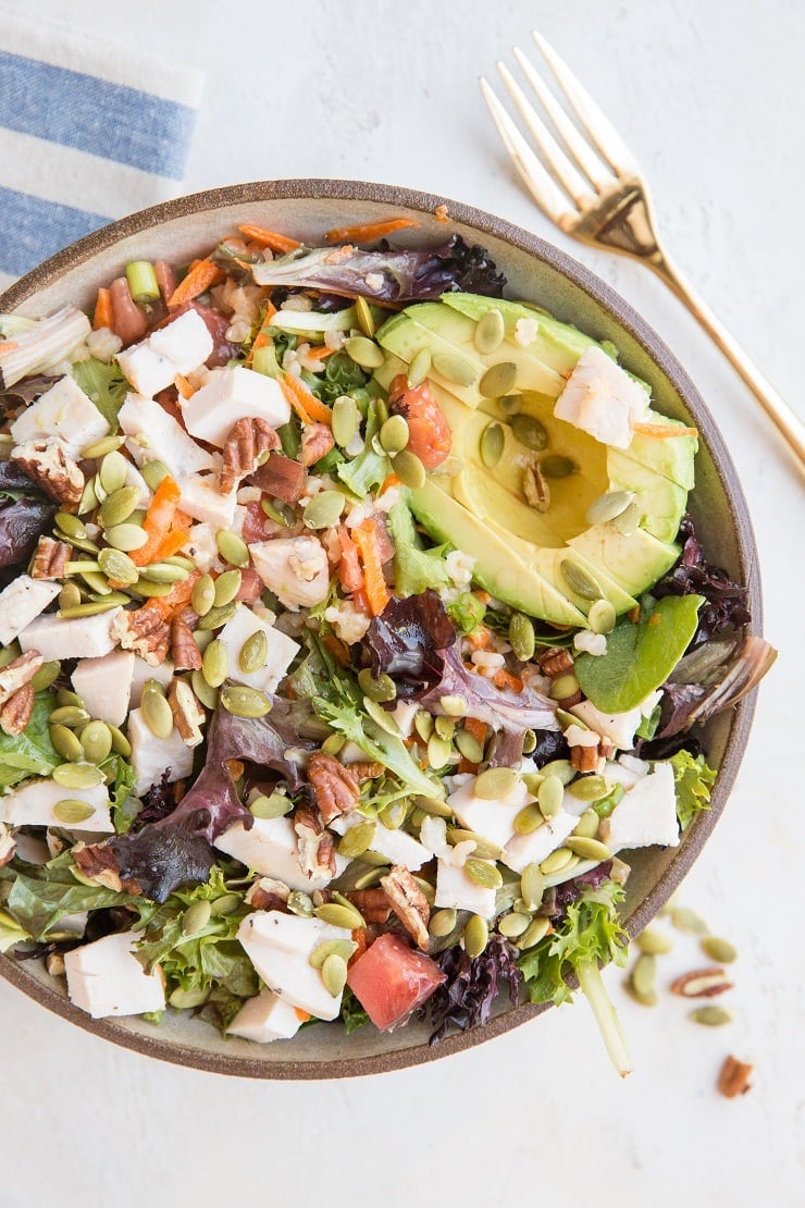Amazing Filling Salad Recipe with chicken, avocado, spring greens, carrot, pumpkin seeds, pecans, green onion, and tomato