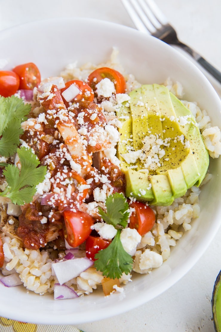 Healthy Chicken Burrito Bowls with tomatoes, onion, avocado, queso fresco, and salsa