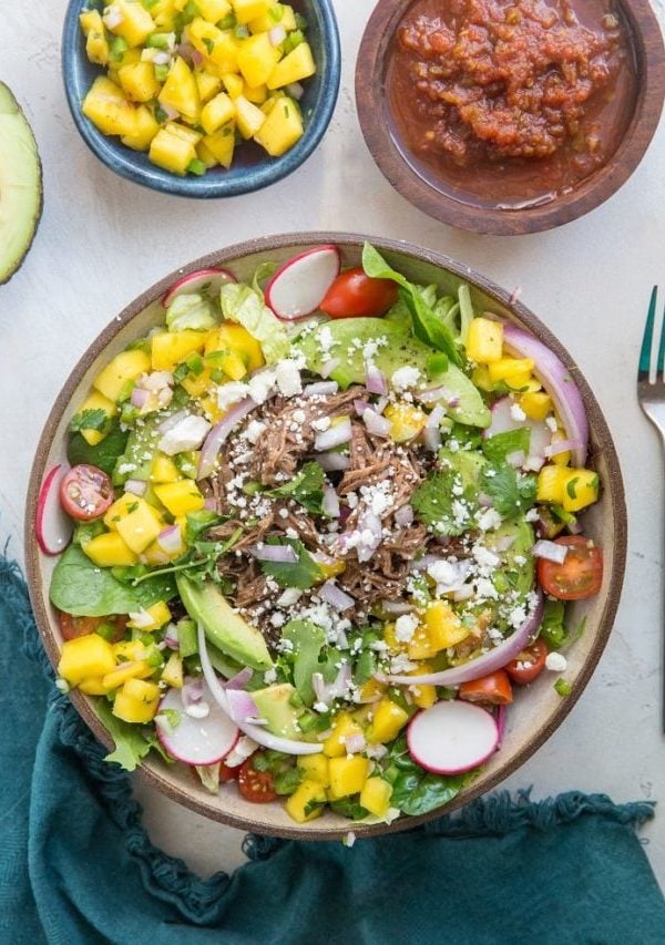 Shredded Beef Taco Salad with spring greens, avocado, cherry tomatoes, mango salsa, and more! A fresh and filling salad recipe!