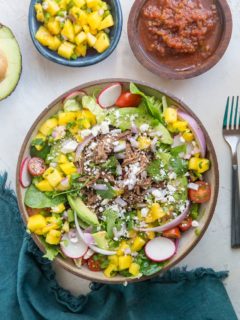 Shredded Beef Taco Salad with spring greens, avocado, cherry tomatoes, mango salsa, and more! A fresh and filling salad recipe!