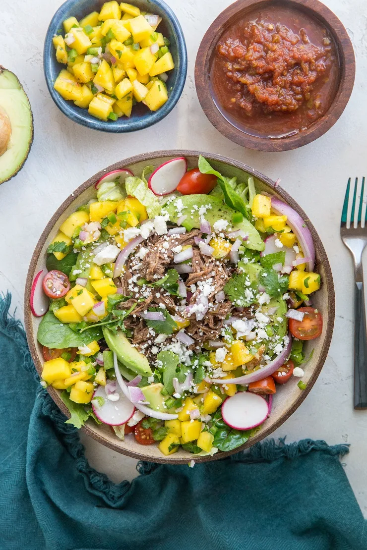 Shredded Beef Taco Salad with spring greens, avocado, cherry tomatoes, mango salsa, and more! A fresh and filling salad recipe!