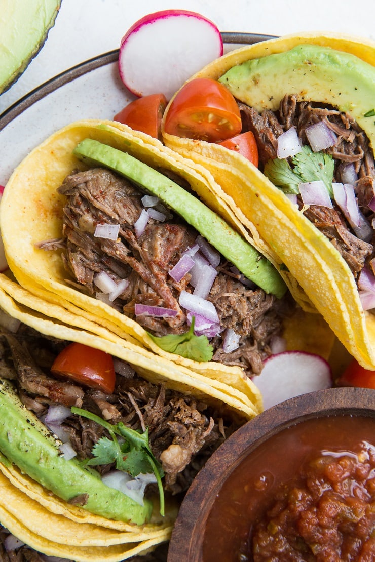 Instant Pot Shredded Beef Tacos with avocado, red onion and salsa. An amazingly flavorful, easy taco recipe!