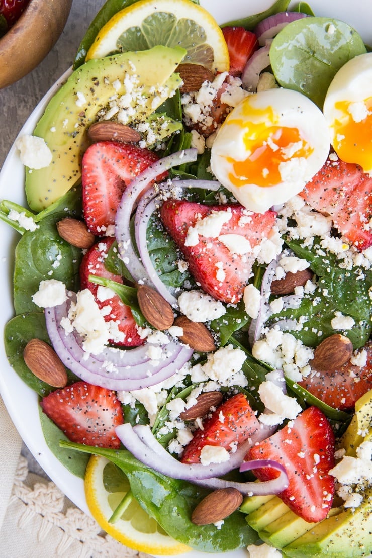 Strawberry Spinach Salad with Poppy Seed Dressing, jammy egg, avocado, roasted almonds, feta, and red onion! A beautiful, delicious salad recipe for any gathering! Amazing side dish or main entrée.