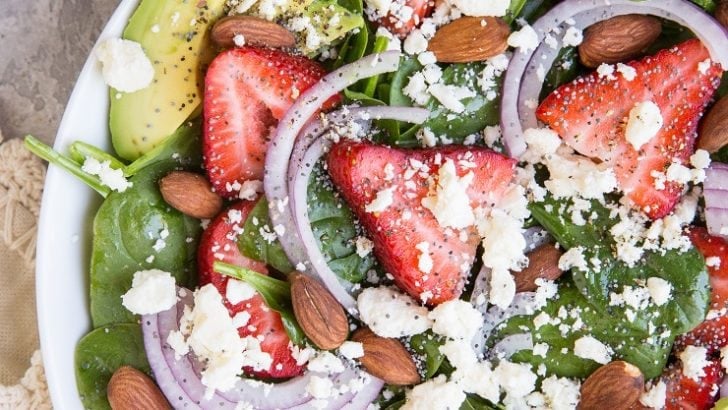 Strawberry Spinach Salad with Poppy Seed Dressing, avocado, roasted almonds, feta, and red onion! A beautiful, delicious salad recipe for any gathering! Amazing side dish or main entrée.