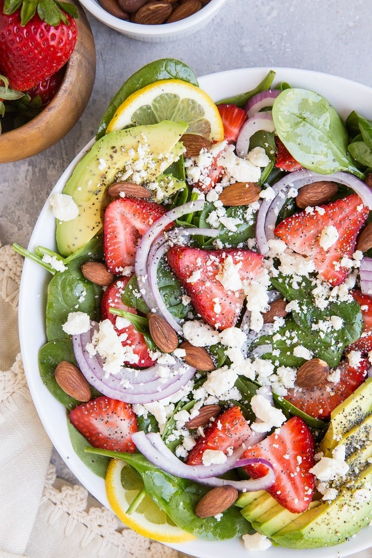 Strawberry Spinach Salad with Poppy Seed Dressing, avocado, roasted almonds, feta, and red onion! A beautiful, delicious salad recipe for any gathering! Amazing side dish or main entrée.