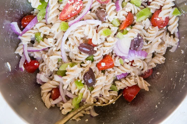 Toss ingredients for pasta salad together in a mixing bowl.