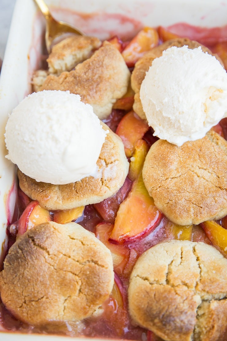 Vegan Paleo Peach Cobbler with almond flour topping and sweetened with pure maple syrup. This easy, healthy summer dessert recipe is grain-free, dairy-free, refined sugar-free and requires only 8 ingredients!