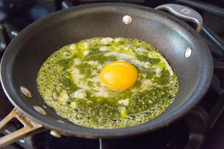 Crack an egg into the center of the pesto sauce