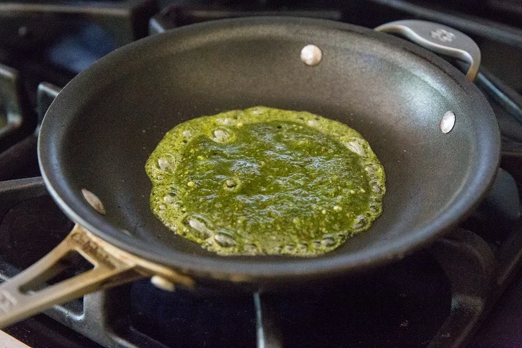 Add pesto sauce to a skillet and allow it to sizzle