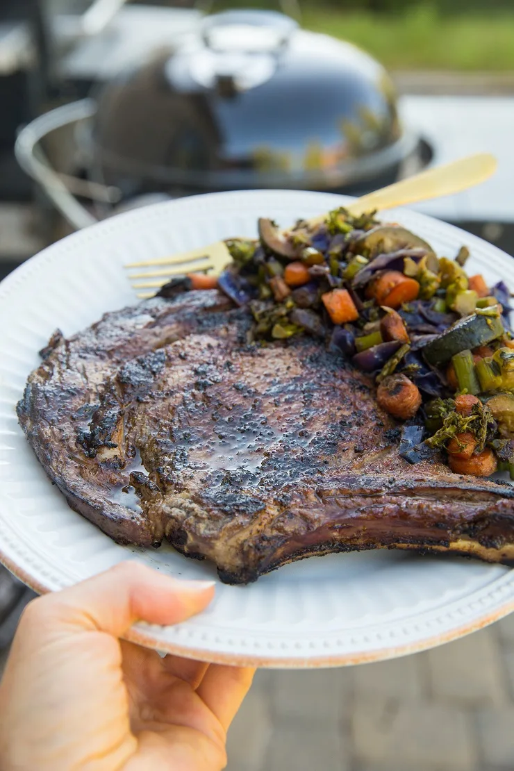 Delicious juicy perfectly grilled bone-in ribeye steak and veggies