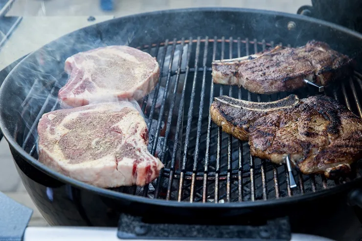 Steaks cooking over direct heat and indirect heat.