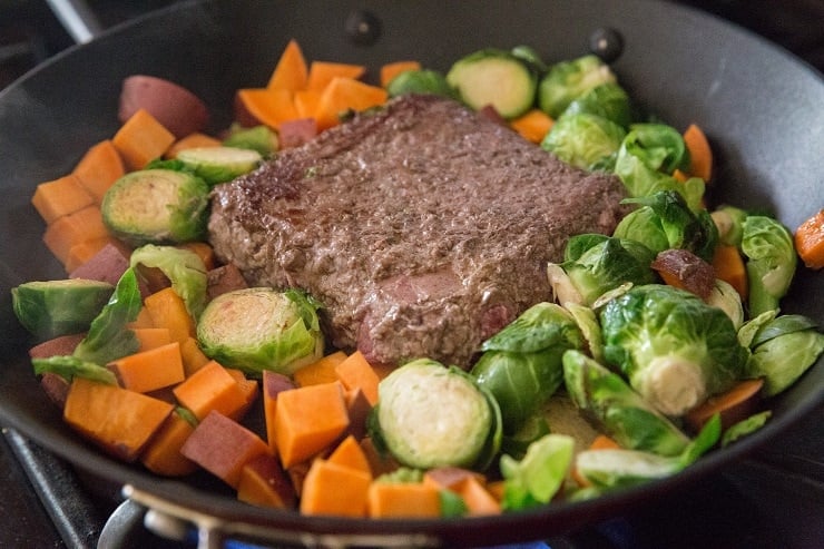 Add all of the ingredients for the recipe to a skillet, placing the ground beef in the center to brown