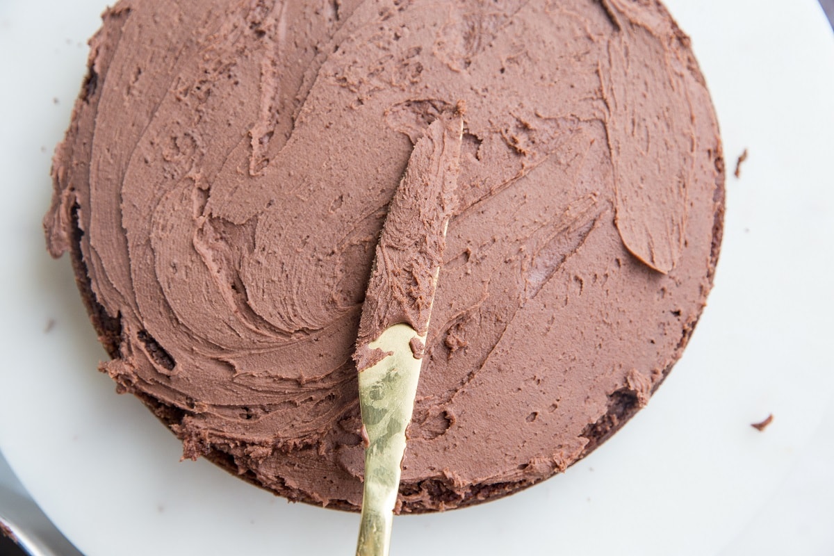 Spreading chocolate buttercream over chocolate cake.