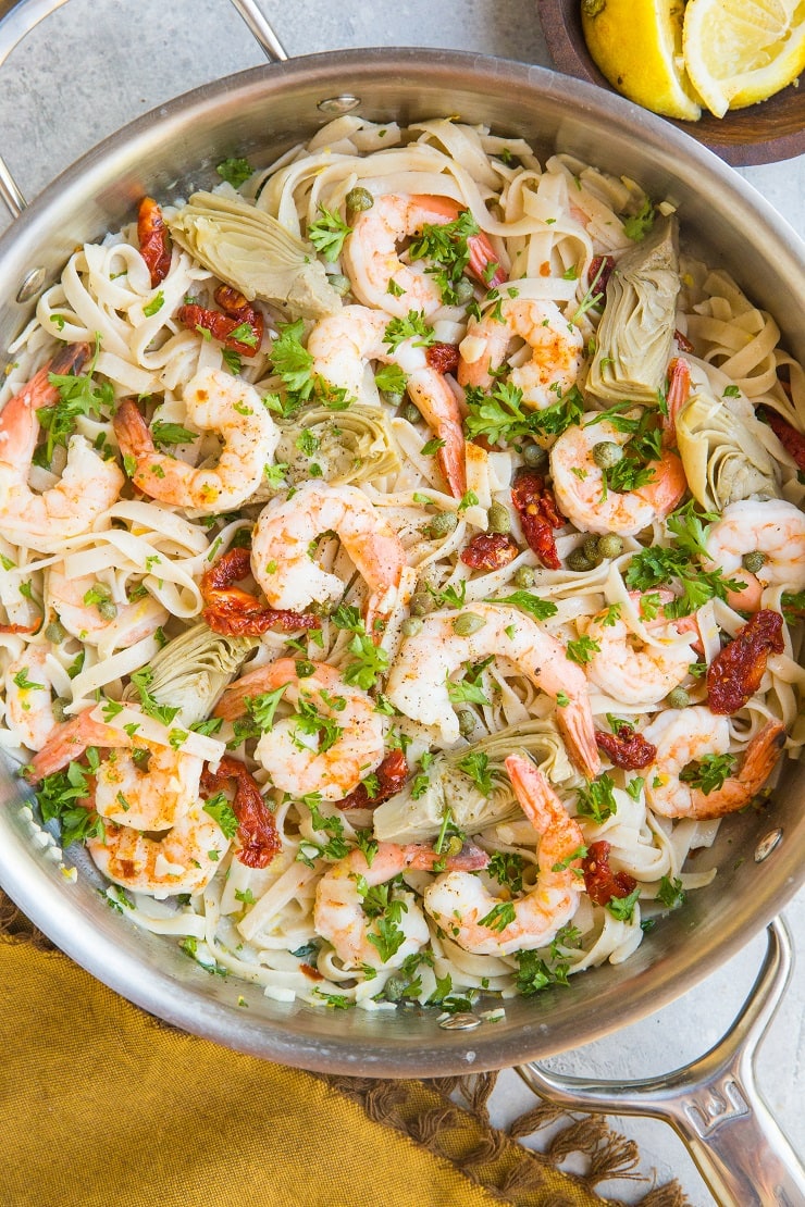 Easy Mediterranean Shrimp Pasta with capers, sun-dried tomatoes, artichoke hearts, and lemon garlic cream sauce. Gluten-free, dairy-free, light and healthy!