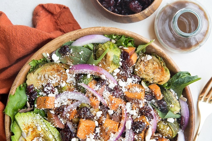 Nutritious superfood Roasted Sweet Potato and Brussel Sprouts Salad with cinnamon balsamic vinaigrette, avocado, dried cranberries, avocado, and more