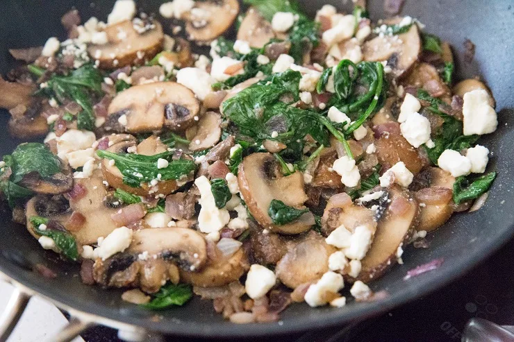 Chicken stuffing mixture in a skillet - mushrooms, onion, spinach and feta cheese