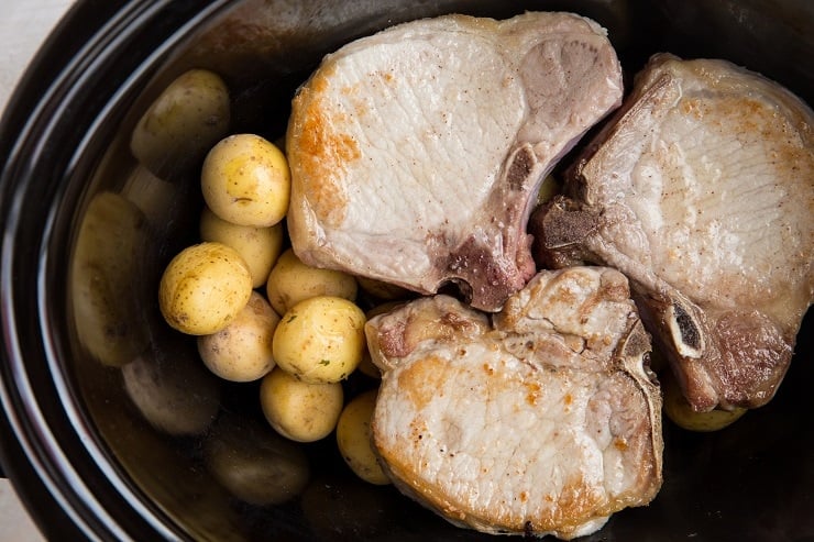Place potatoes at the bottom of the crock pot then place the seared pork chops on top