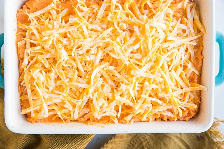 Transfer mashed sweet potatoes to a casserole dish and sprinkle with grated cheese