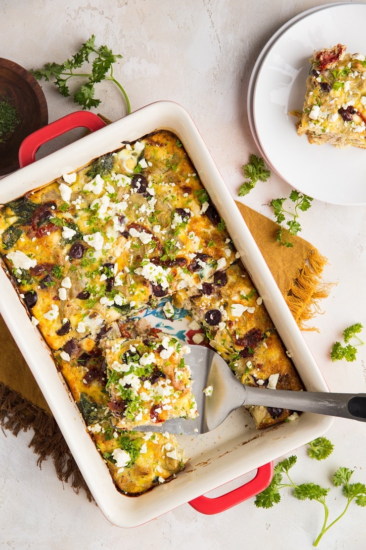 Greek Sausage Breakfast Casserole with sun-dried tomatoes, feta, spinach, kalamata olives and artichoke hearts is a marvelously flavorful meal reminiscent of Mediterranean style meals. This easy egg casserole can be made ahead of time and saves very well for entertaining guests.