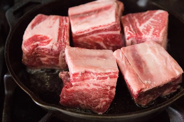 Season the short ribs with sea salt and sear in a cast iron skillet.