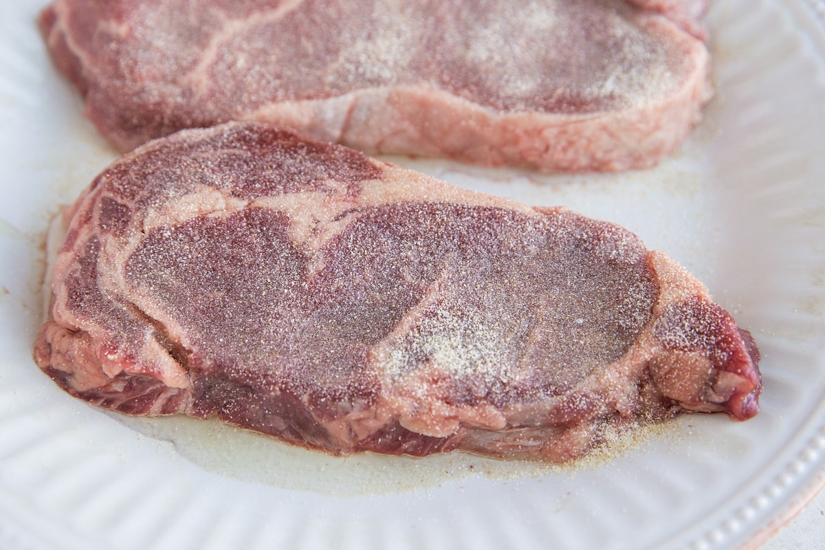 Steaks on a plate coated with oil and seasonings