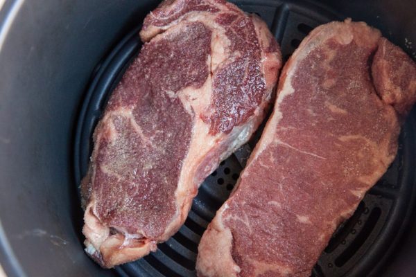 raw steaks in an air fryer basket