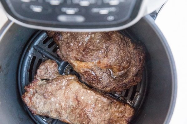 Two cooked steaks in an air fryer