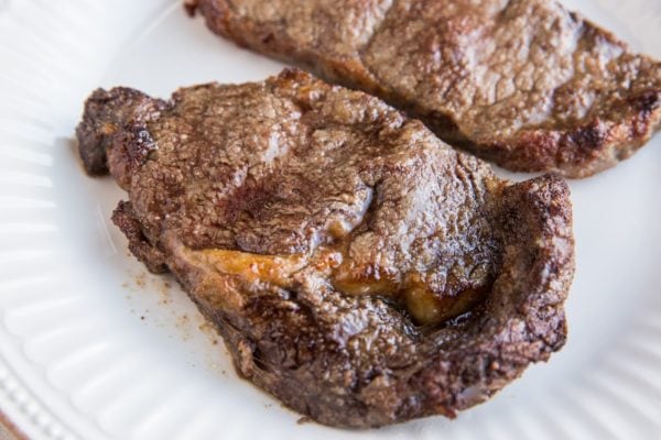 Two cooked steaks on a plate resting