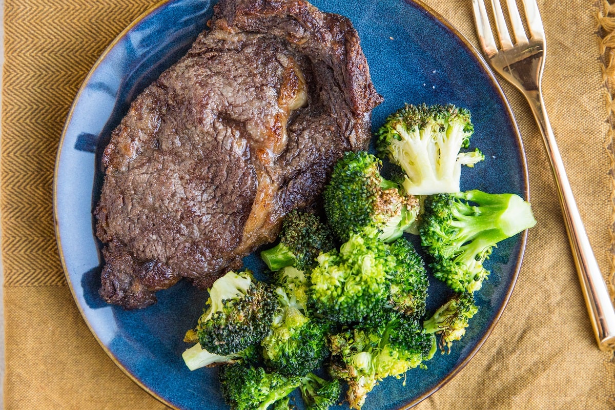 Horizontal photo of steak and broccoli on a blue plate