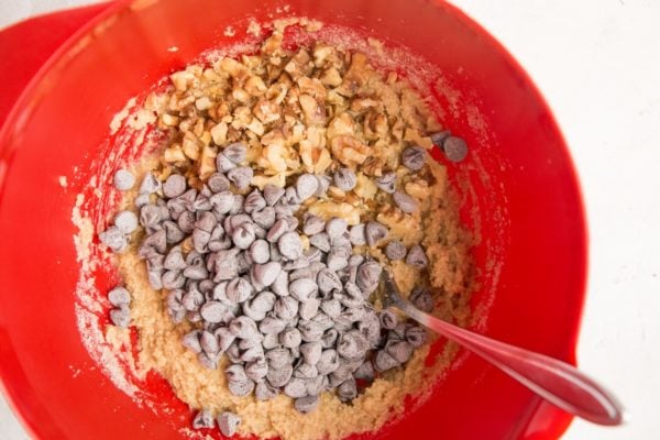 Cookie dough in a mixing bowl with chocolate chips and walnuts