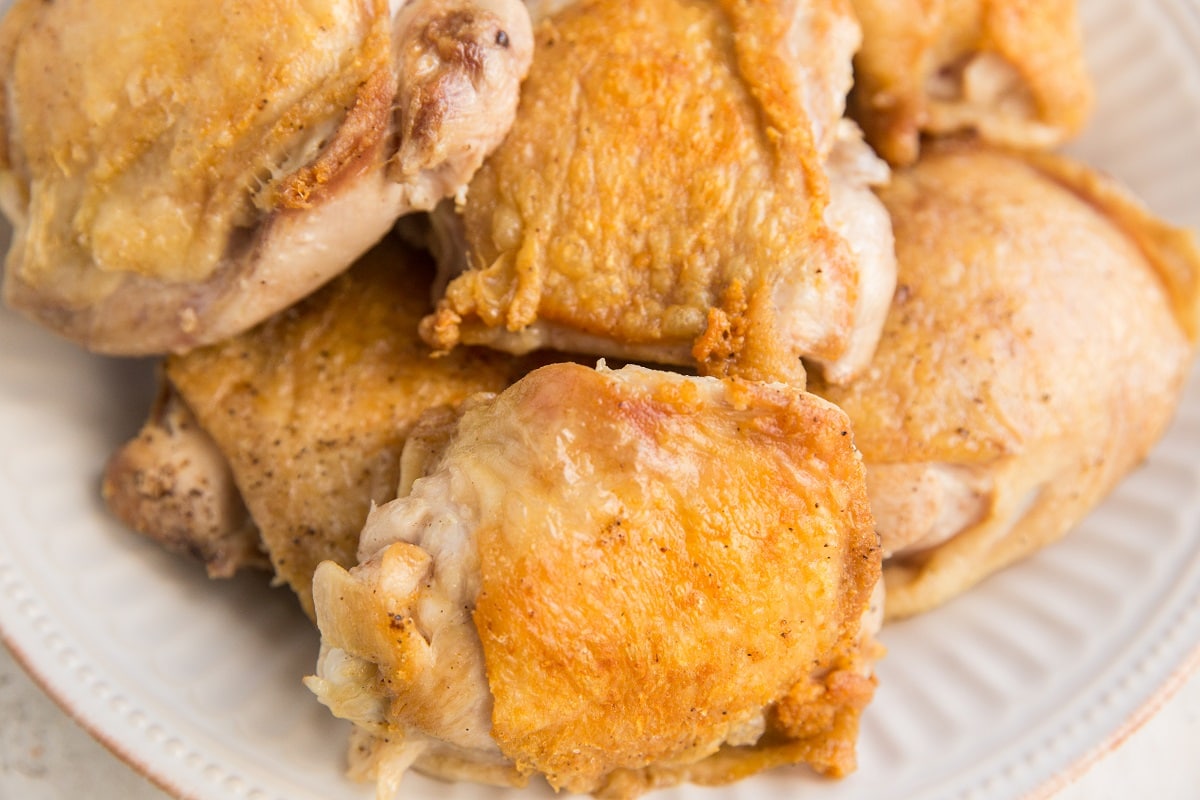 Pan-seared chicken thighs with golden-brown skin on a white plate