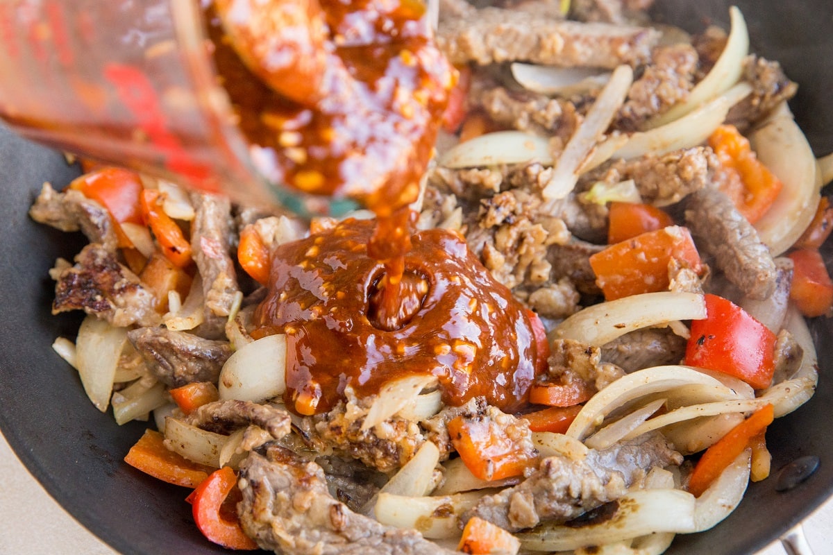 Sauce being poured over the stir fry beef and veggies