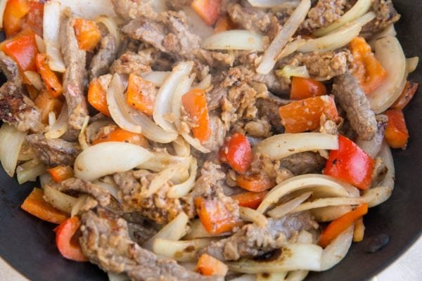 beef, onion and bell pepper sautéing in a skillet