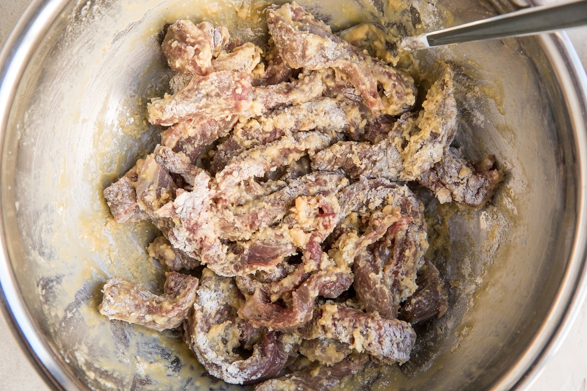 Raw beef in a mixing bowl tossed in flour