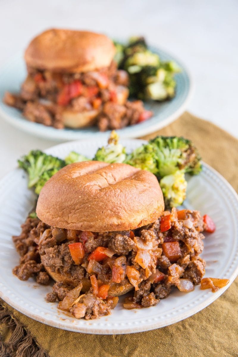 Two plates of sloppy joes with a side of roasted broccoli