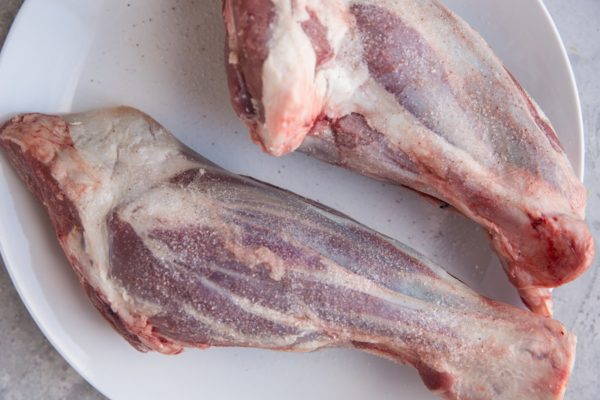 Lamb shanks on a plate sprinkled with salt