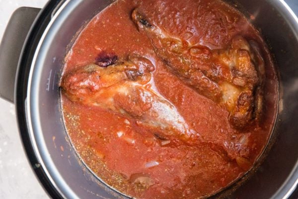 Lamb shanks in a pressure cooker covered in sauce