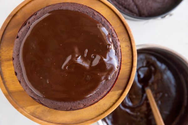 One of the brownie cakes on a cakes stand with ganache spread over the top