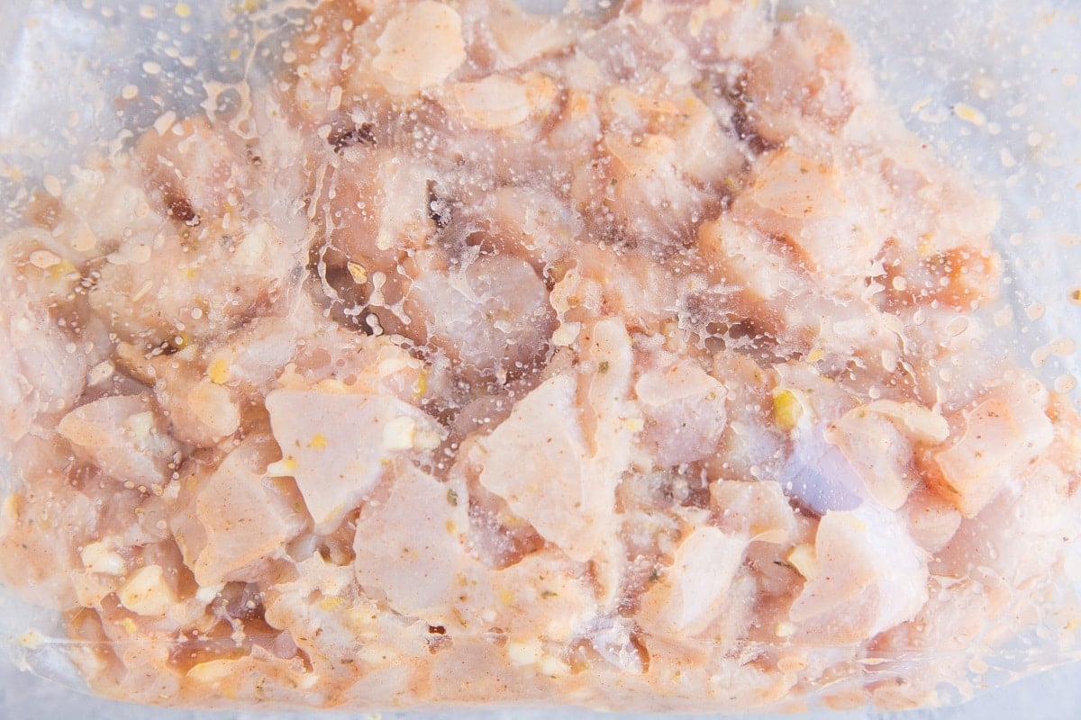 Chicken marinating in a zip lock with oil, lemon zest, lemon juice, garlic, and more