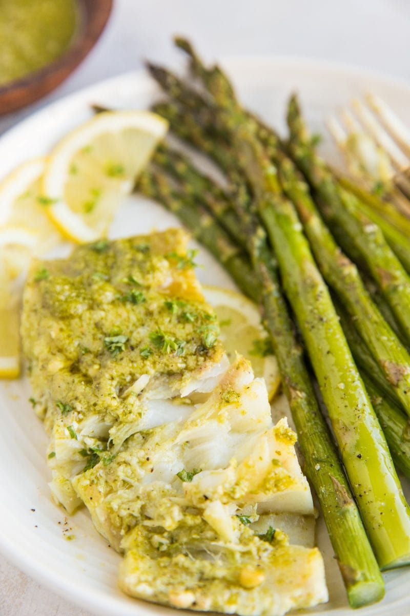 Plate of pesto cod with asparagus and slices of lemon
