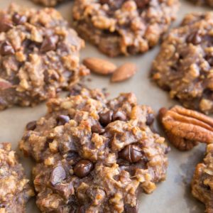 Baking sheet with nutty banana cookies with raw almonds and pecans next to the cookies