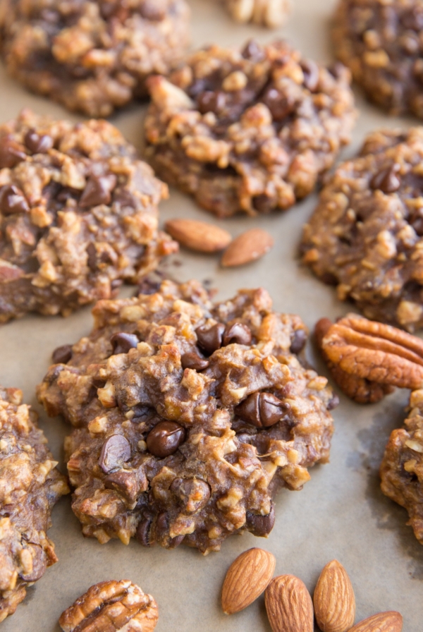 Baking sheet with nutty banana cookies with raw almonds and pecans next to the cookies