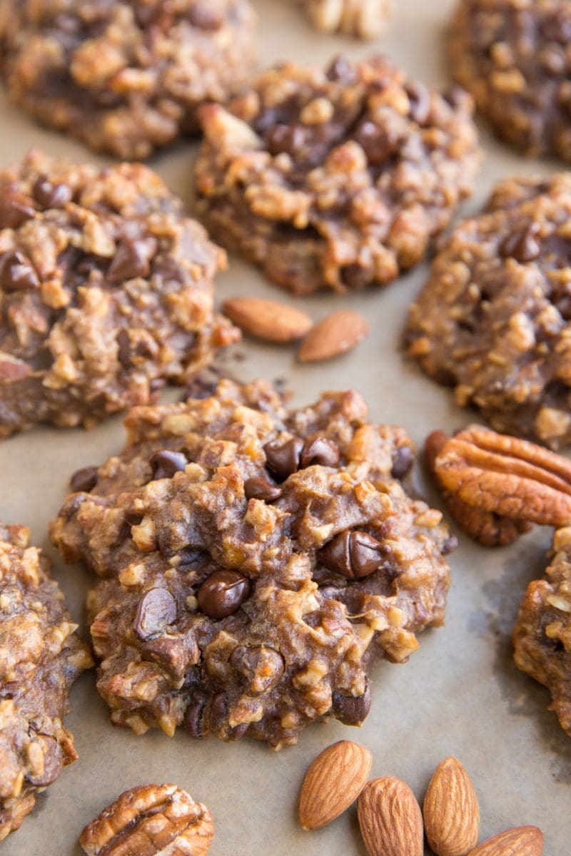 Baking sheet with nutty banana cookies with raw almonds and pecans next to the cookies