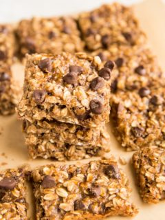 Stack of oatmeal bars sitting on parchment paper with oatmeal bars to the side