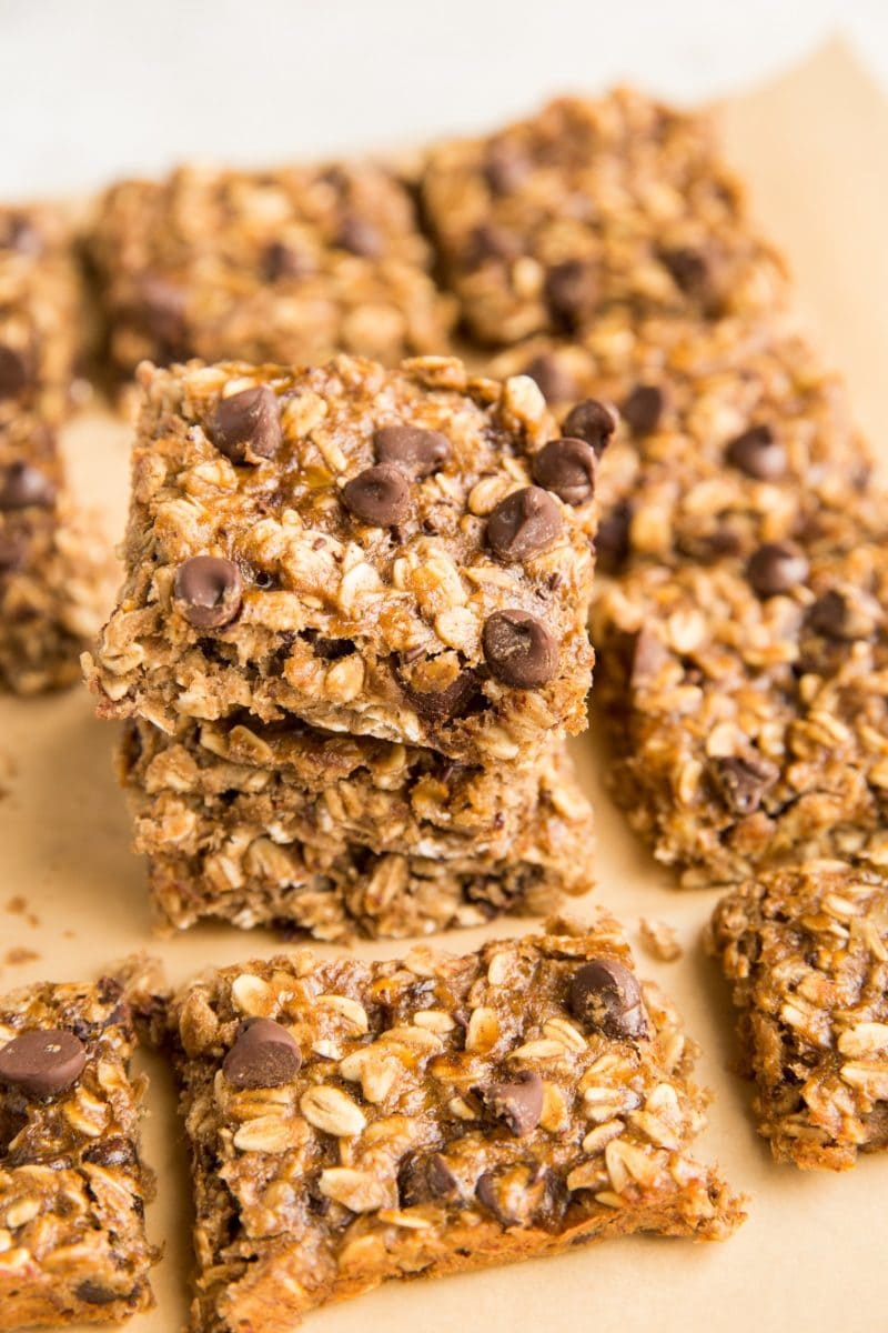 Stack of oatmeal bars sitting on parchment paper with oatmeal bars to the side
