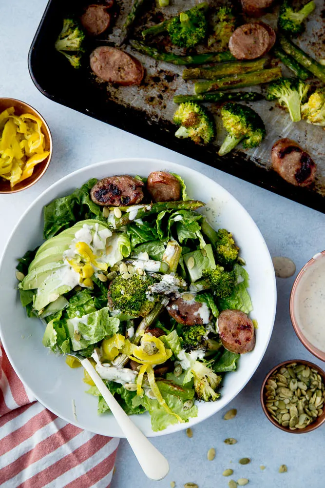 Roasted veggies and lettuze, avocado and sausage in a bowl