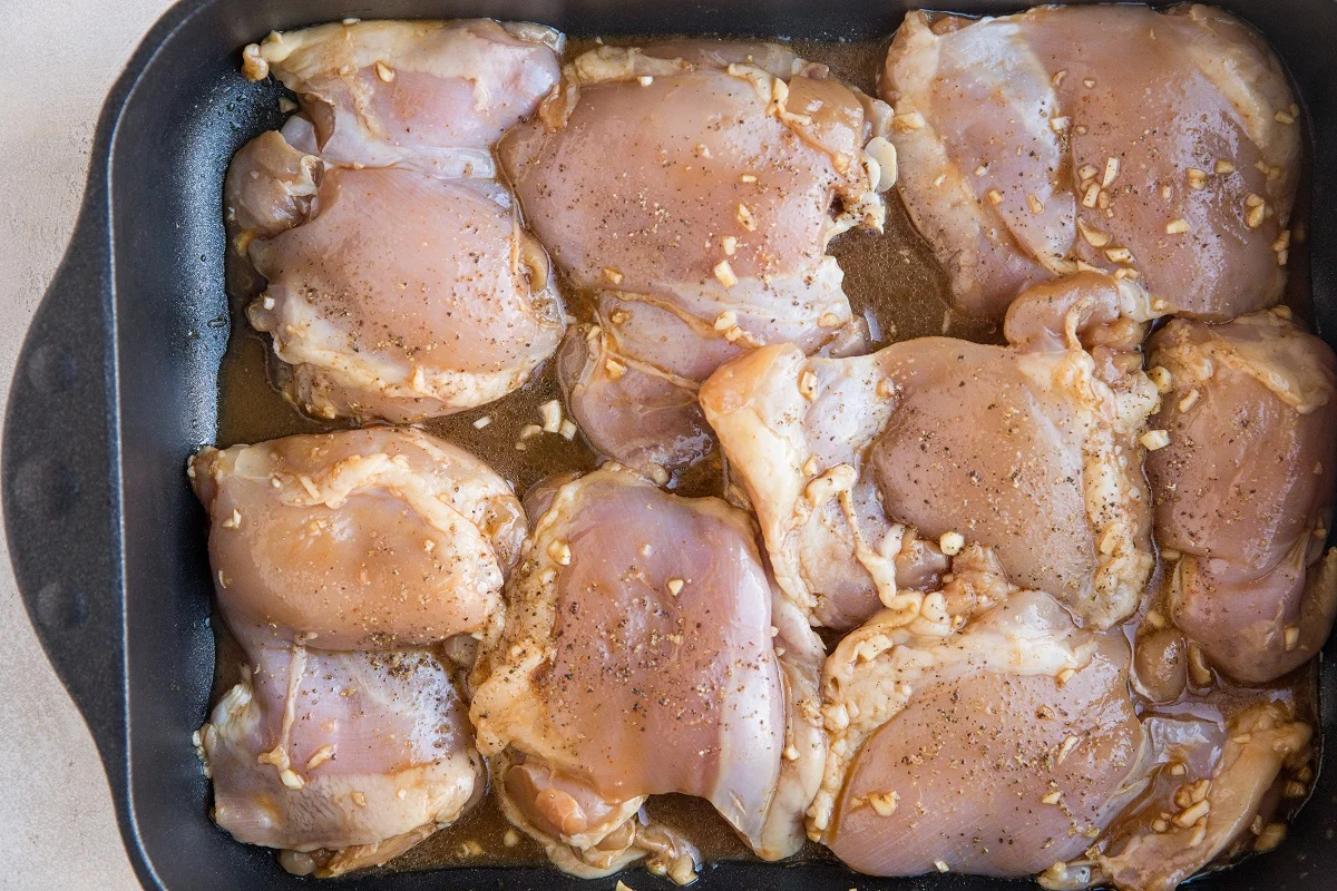 Chicken thighs in a casserole dish in marinade, waiting to go into the oven