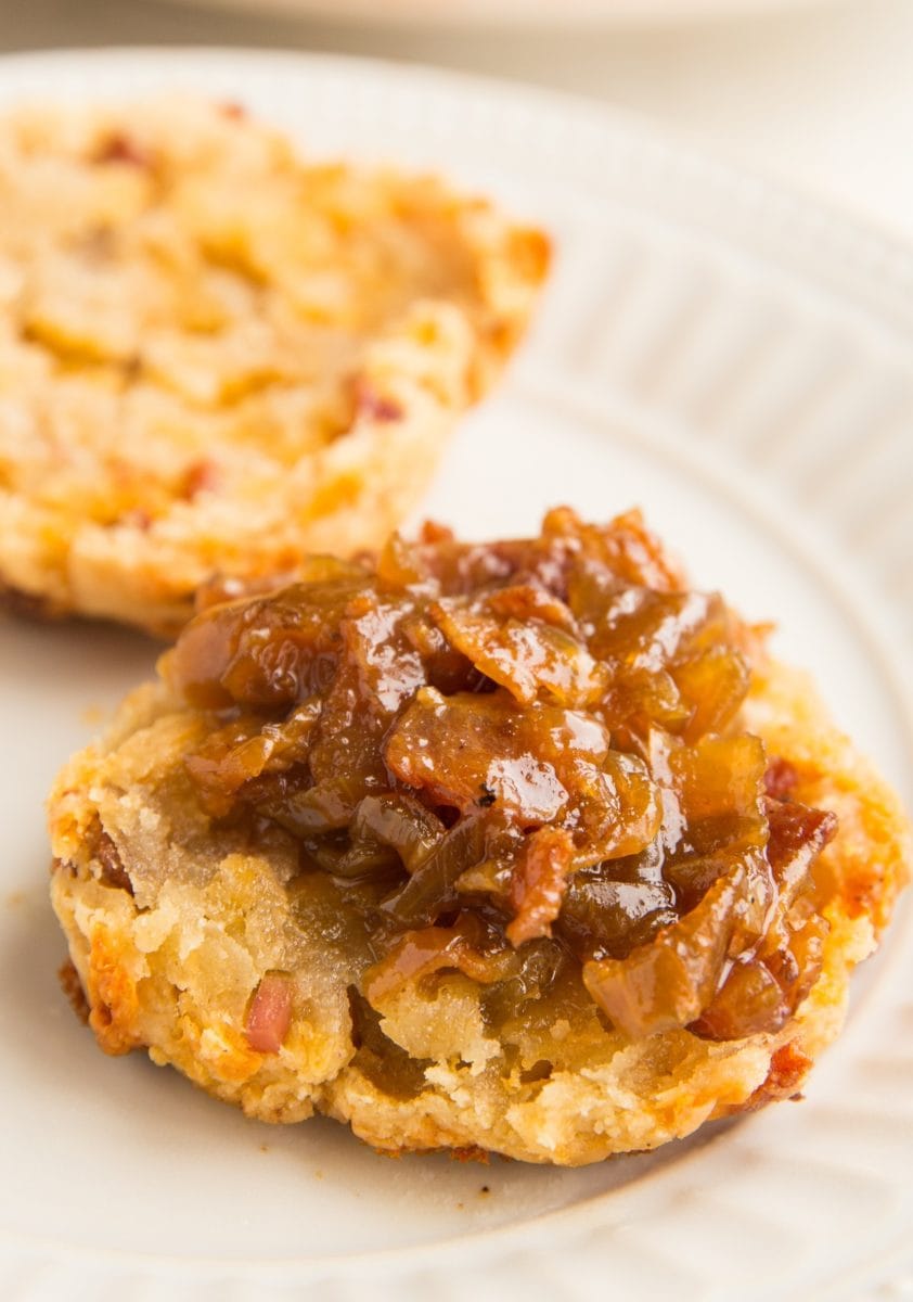 Biscuit on a white plate with bacon jam on top