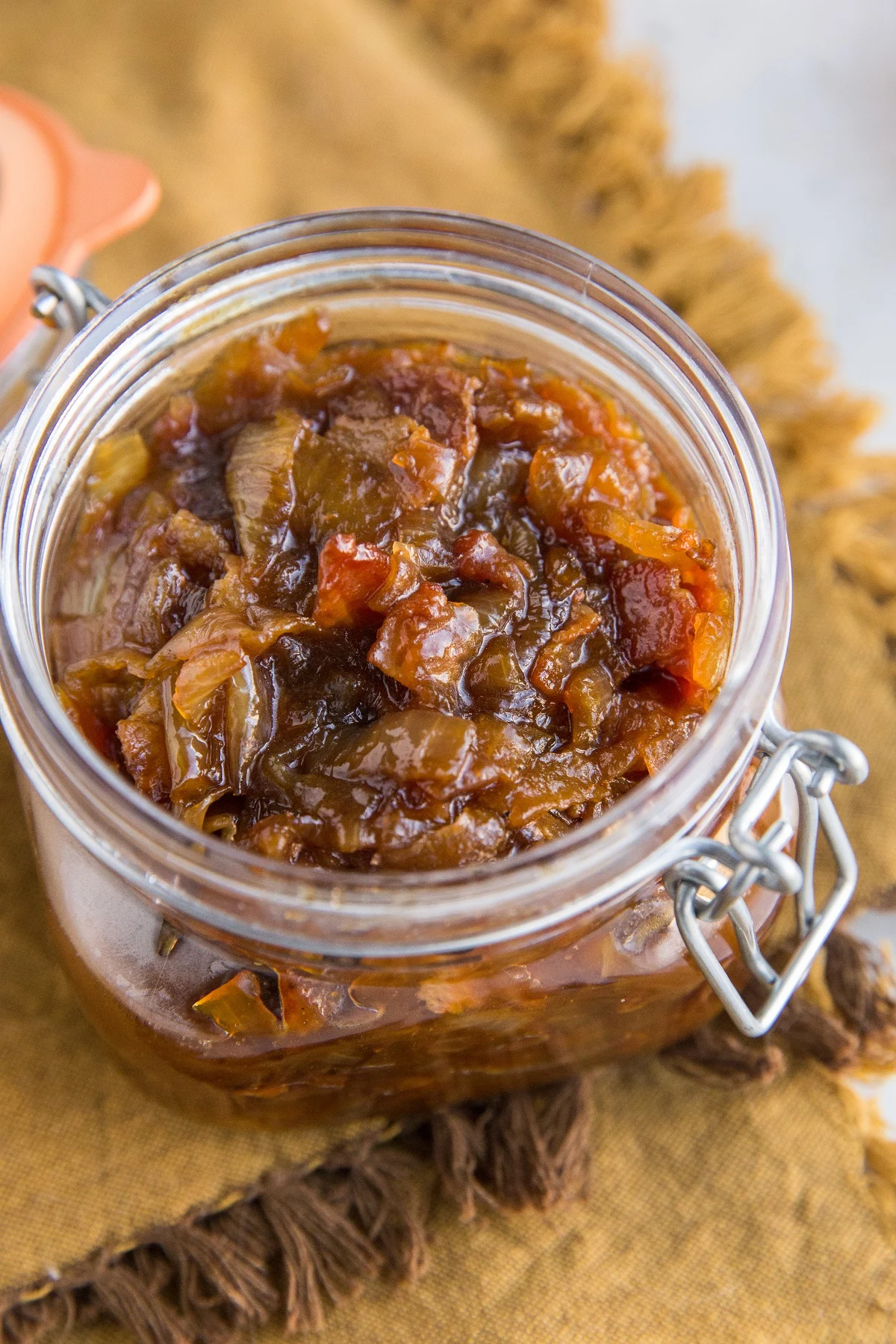 Jar full of freshly made bacon jam on top of a golden-brown napkin